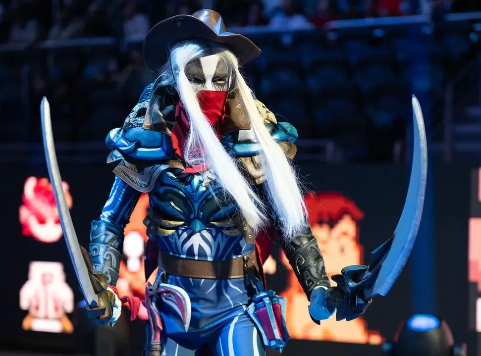 A performer in blue armour and a white-haired mask holding two swords